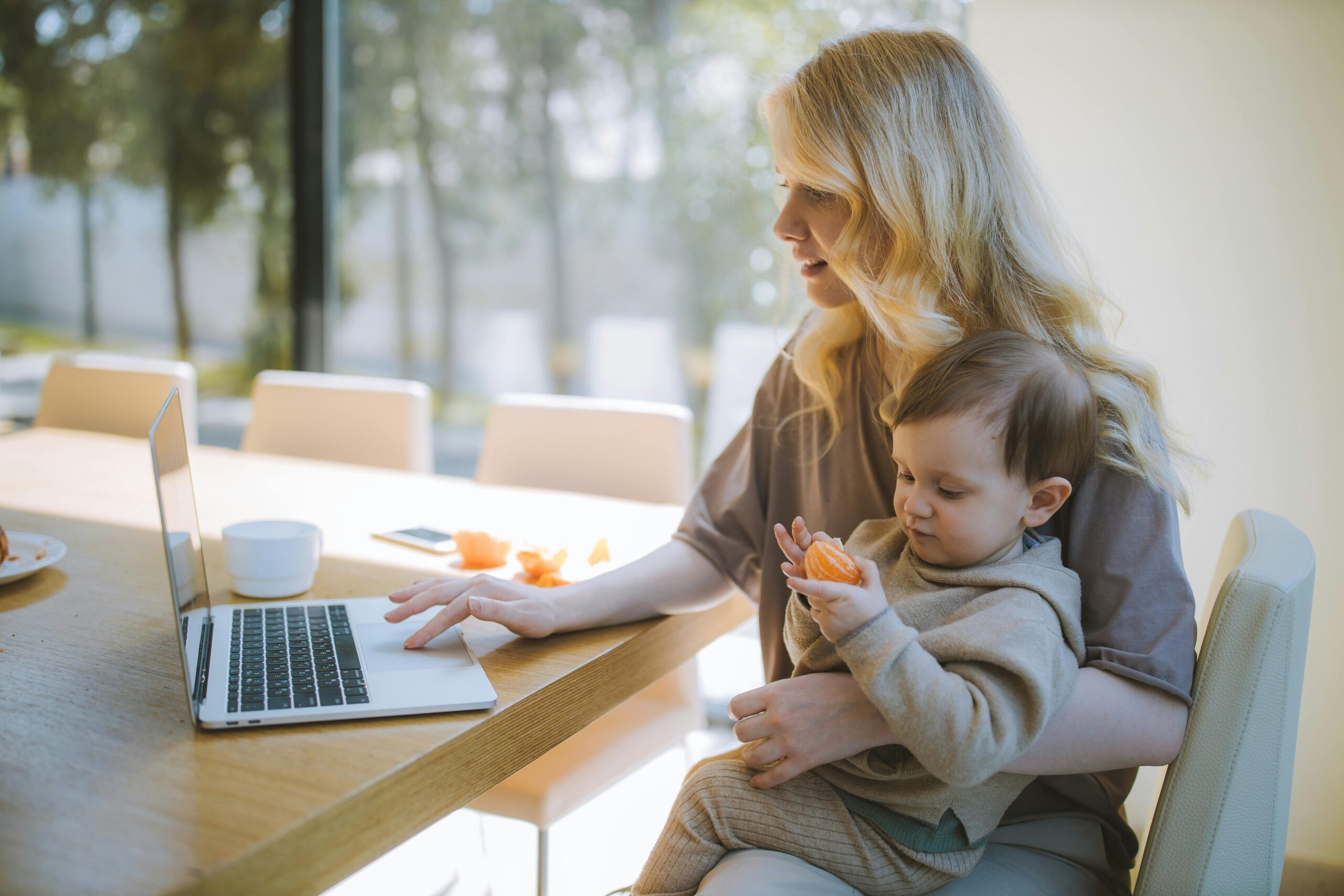 mujer-sentada-con-su-bebe-en-brazos-mirando-en-un-portatil-las-bonificaciones-en-la-cuota-de-autonomos